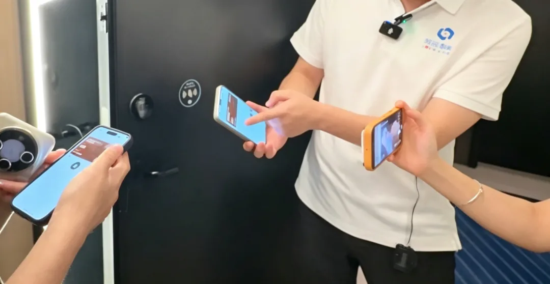 猫耳朵成都旗舰店客房现场：多只手同时将手机贴近黑色客房门锁的圆形 NFC 感应区，手机屏幕显示开锁界面，展示 LS02 Ultra 联网版手机开门